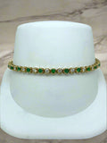 Bracelet with green and clear stones on a white stand