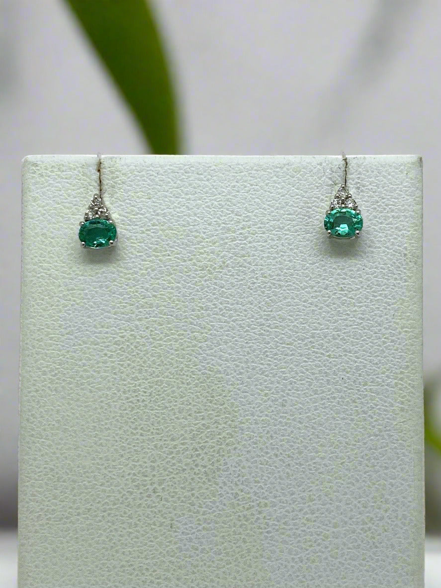 Pair of emerald earrings on a light gray display card