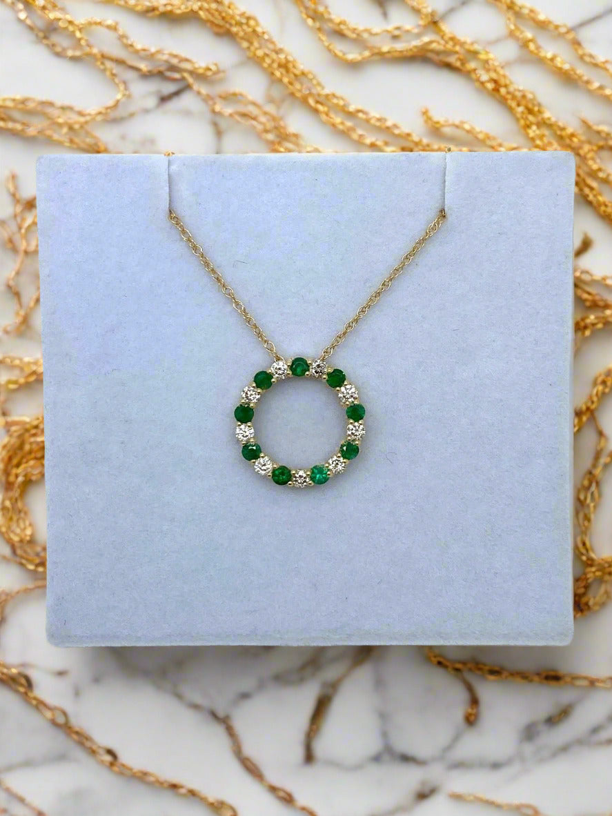 Gold necklace with emeralds and diamonds in a circular pendant on a gold chain