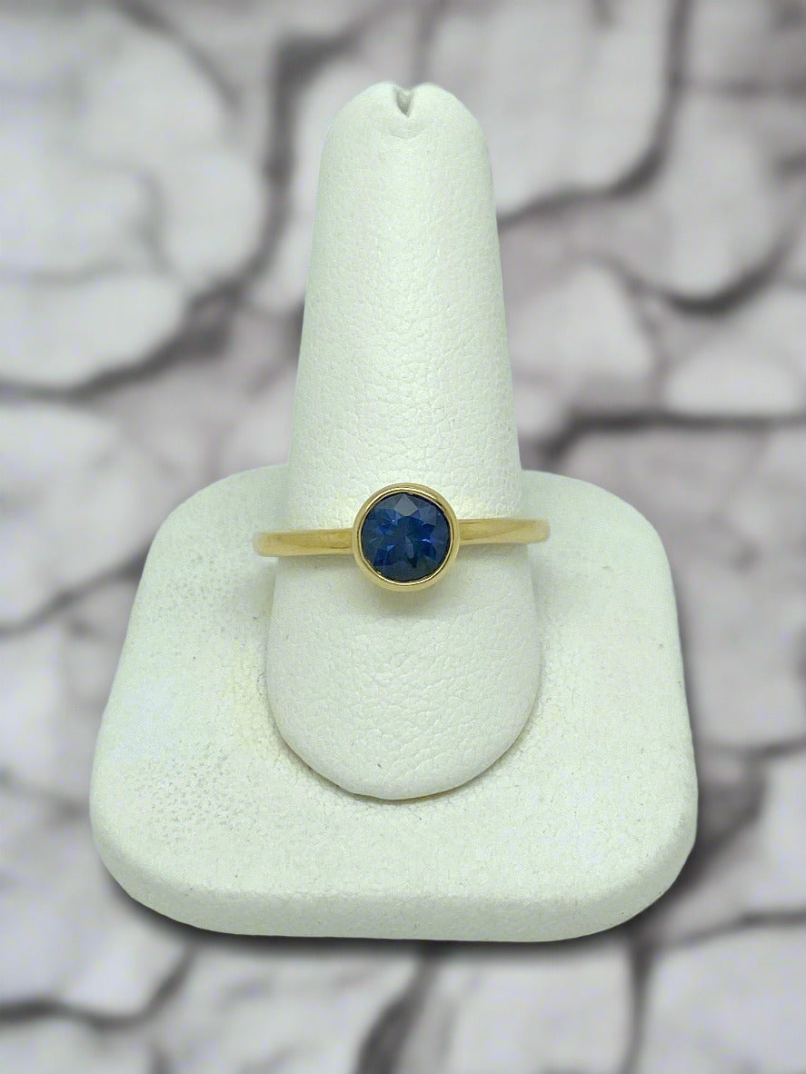 yellow gold ring with bezel set round blue sapphire