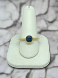 yellow gold ring with bezel set round blue sapphire