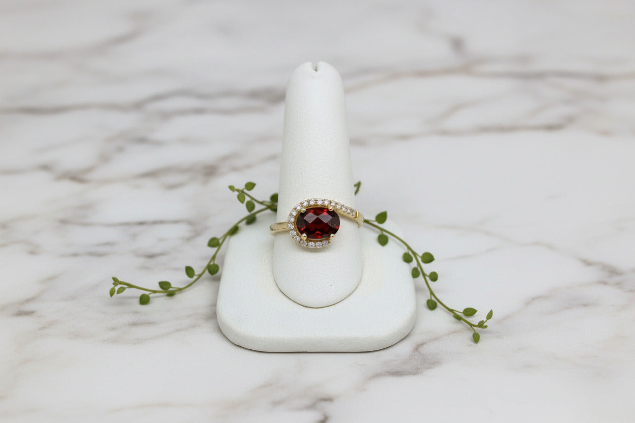 yellow gold ring with oval garnet and asymmetric diamond swirl accent