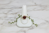 yellow gold ring with oval garnet and asymmetric diamond swirl accent