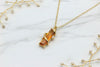 yellow gold necklace with elongated lab-grown padparadscha pendant with diamond accents