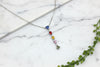 white gold necklace with multi-colored sapphires dangling as a pendant