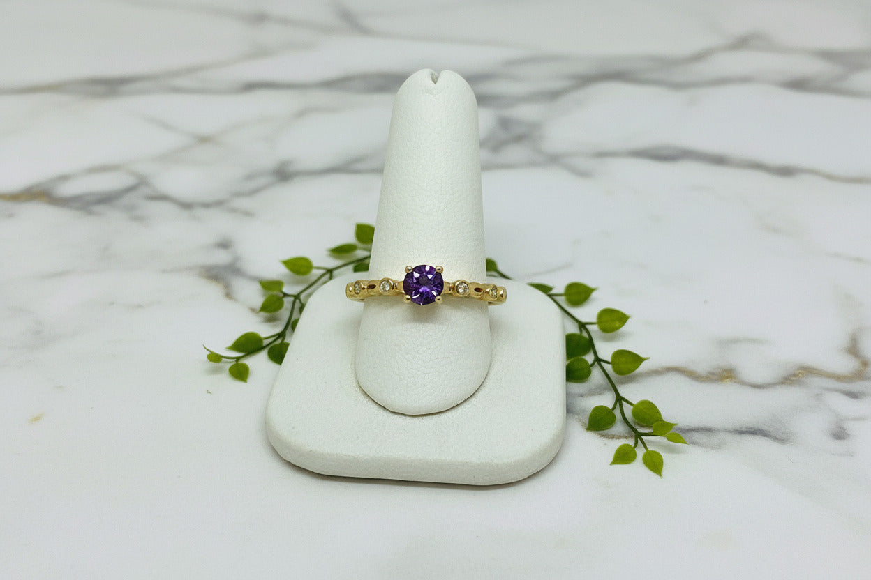 yellow gold ring with round amethyst center stone accented by bezel set diamonds