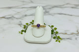 yellow gold ring with round amethyst center stone accented by bezel set diamonds