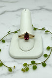 yellow gold split-shank ring with pear cut garnet center stone and two rows of diamonds
