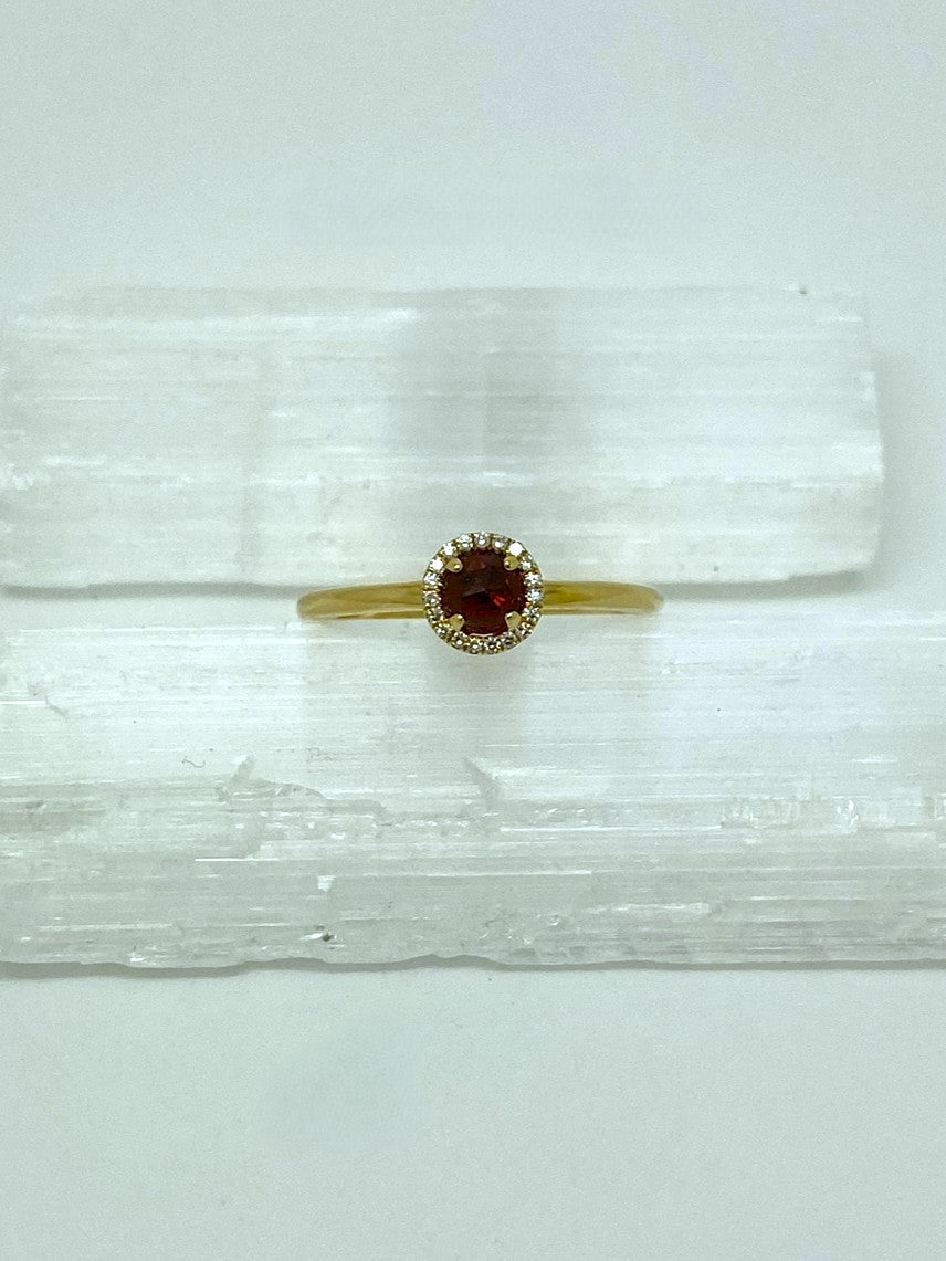 yellow gold ring with round garnet center stone in a halo of diamonds