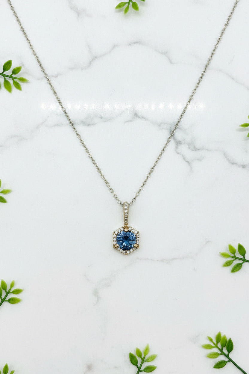 white gold necklace with drop pendant set with round blue spinel center stone in a halo of diamonds