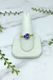 yellow gold ring with asymmetrically set trillion cut tanzanite with 3 diamond accents