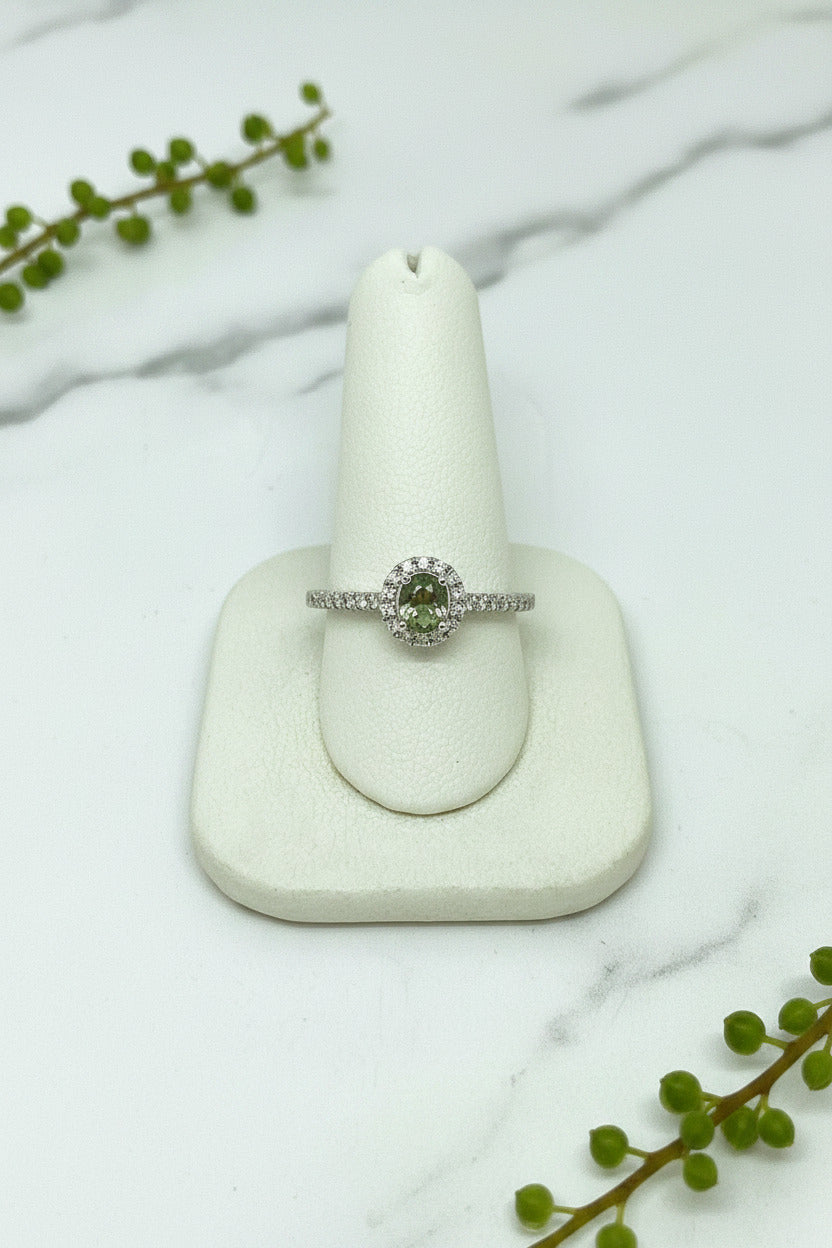 white gold ring set with round natural alexandrite in center and diamond halo as well as accent diamonds down the band