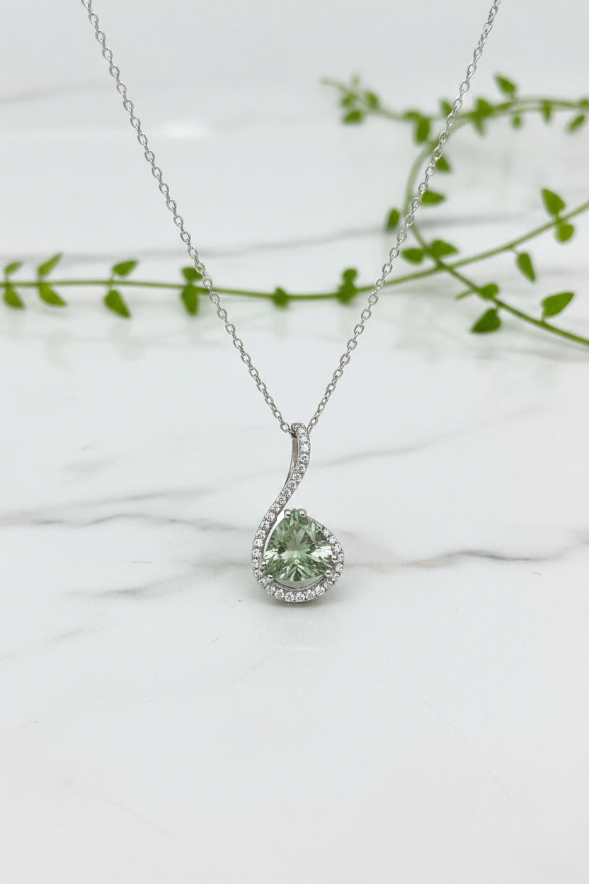 white gold chain and pendant with ribbon of diamonds curling around a trillion cut prasolite