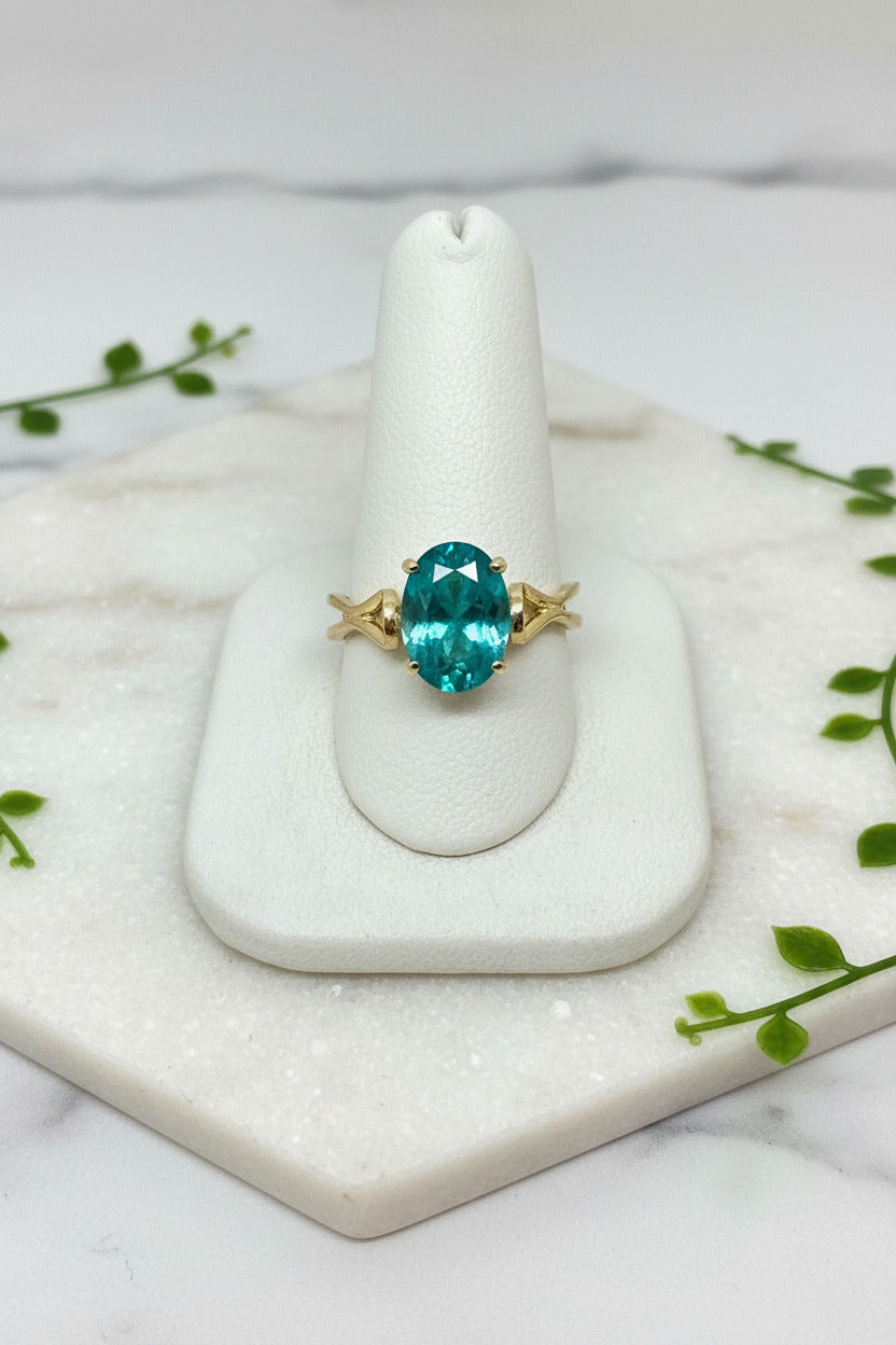 yellow gold ring with wavy band design set with oval green paraiba garnet
