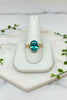 yellow gold ring with wavy band design set with oval green paraiba garnet