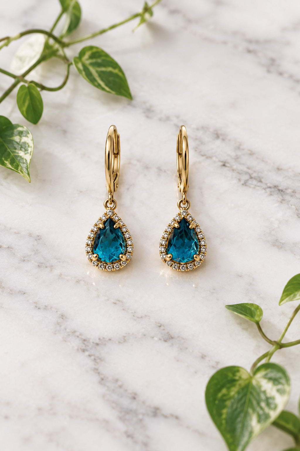 yellow gold dangle earrings with pear-shaped london blue topaz center stones, surrounded in halo of diamonds
