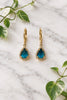 yellow gold dangle earrings with pear-shaped london blue topaz center stones, surrounded in halo of diamonds