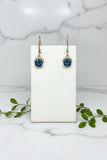 pair of yellow gold dangle earrings with blue topaz center stone and line of diamonds above