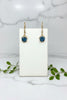 pair of yellow gold dangle earrings with blue topaz center stone and line of diamonds above