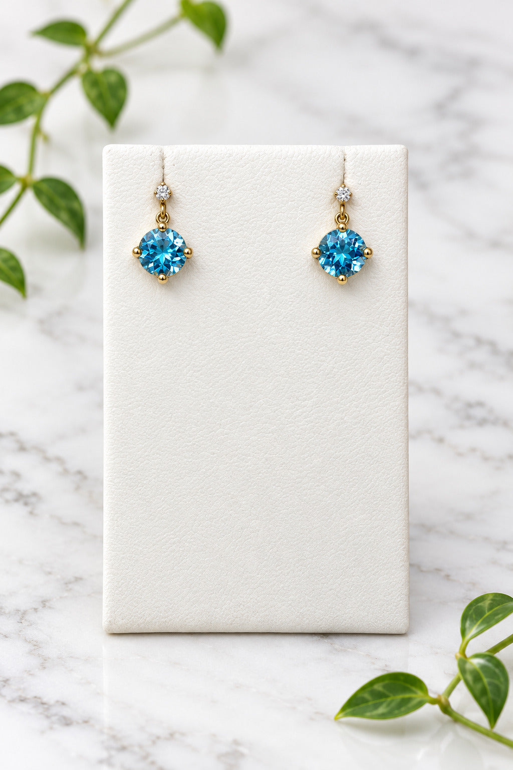 yellow gold dangle earrings with round swiss blue topaz center stones and a diamond accent on each