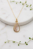 yellow gold chain and pendant, pendant is a teardrop with swirl on top set with morganite stones